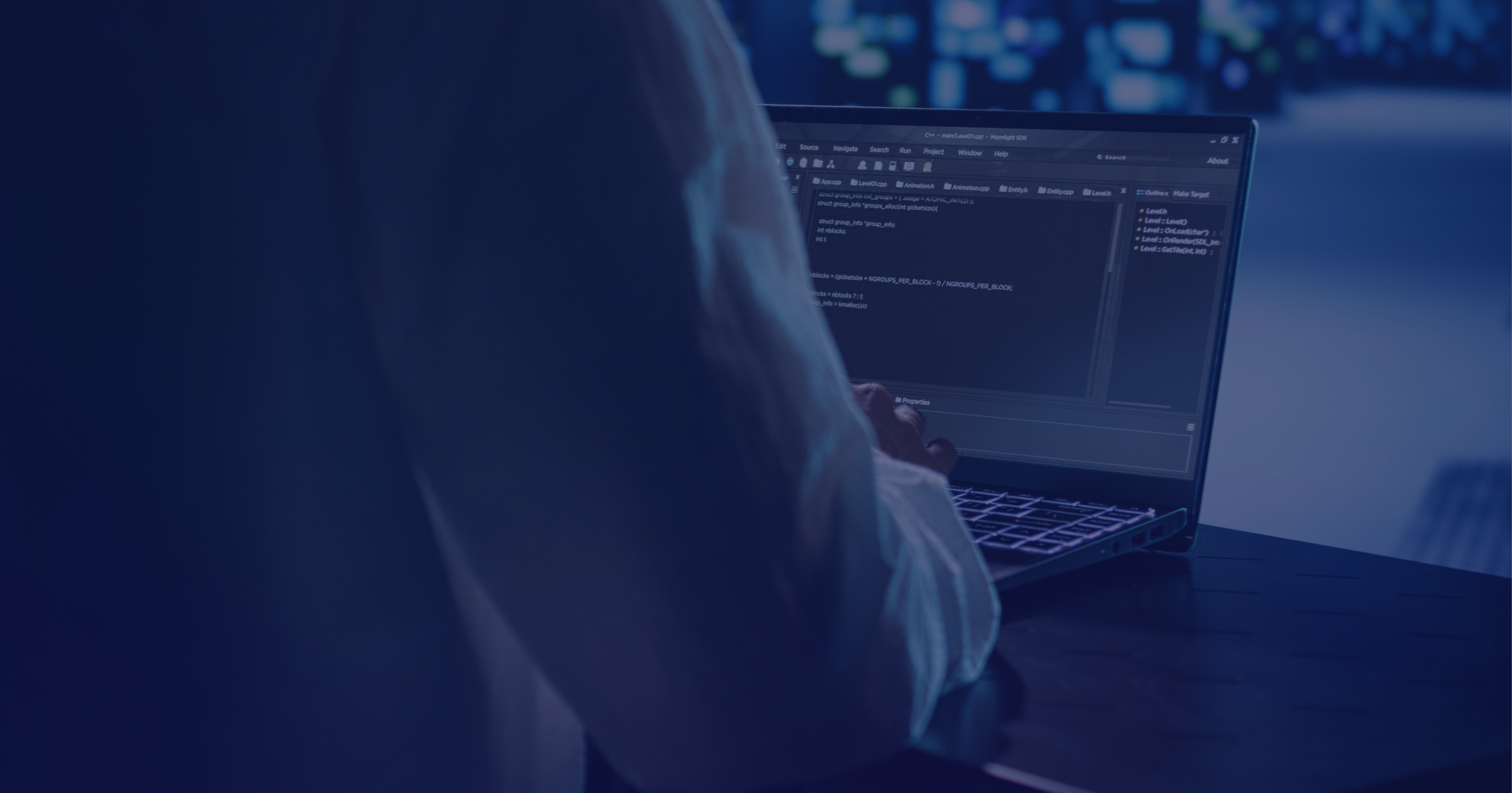 Developer working on code with laptop screen showing programming interface.