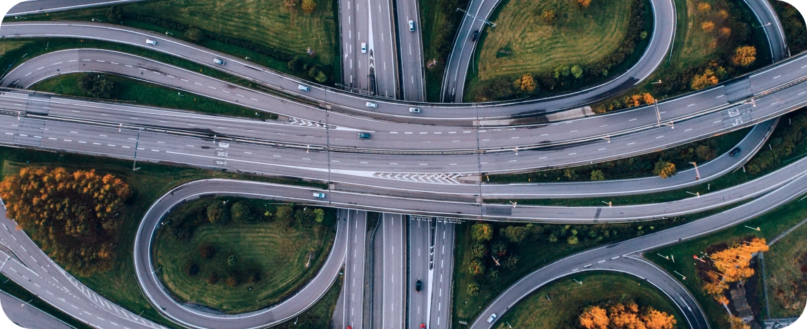 Aerial drone view of complex highway interchange with multiple curved ramps and overpasses showing modern transportation infrastructure surrounded by autumn foliage.