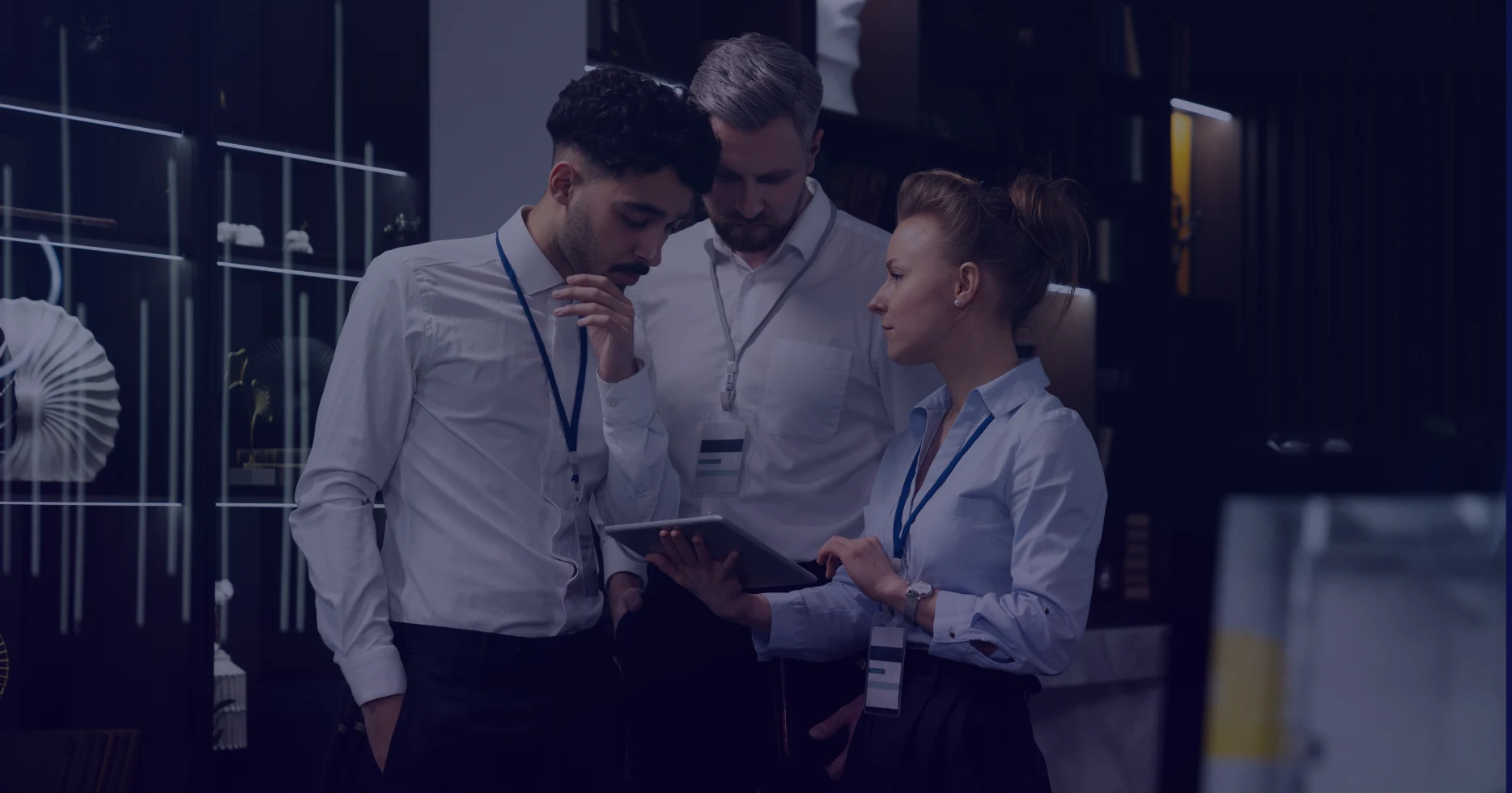 Team collaboration on business strategy, with one person holding a tablet while discussing insights in a corporate environment.